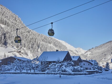 Ein Skifahrer fährt die schneebedeckte Piste hinunter. Im Hintergrund sind majestätische Berge zu sehen.