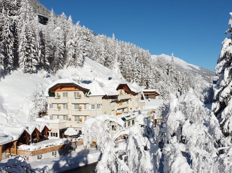 A picturesque hotel in a snow-covered landscape. Tall pine trees and blue sky create a winter atmosphere.